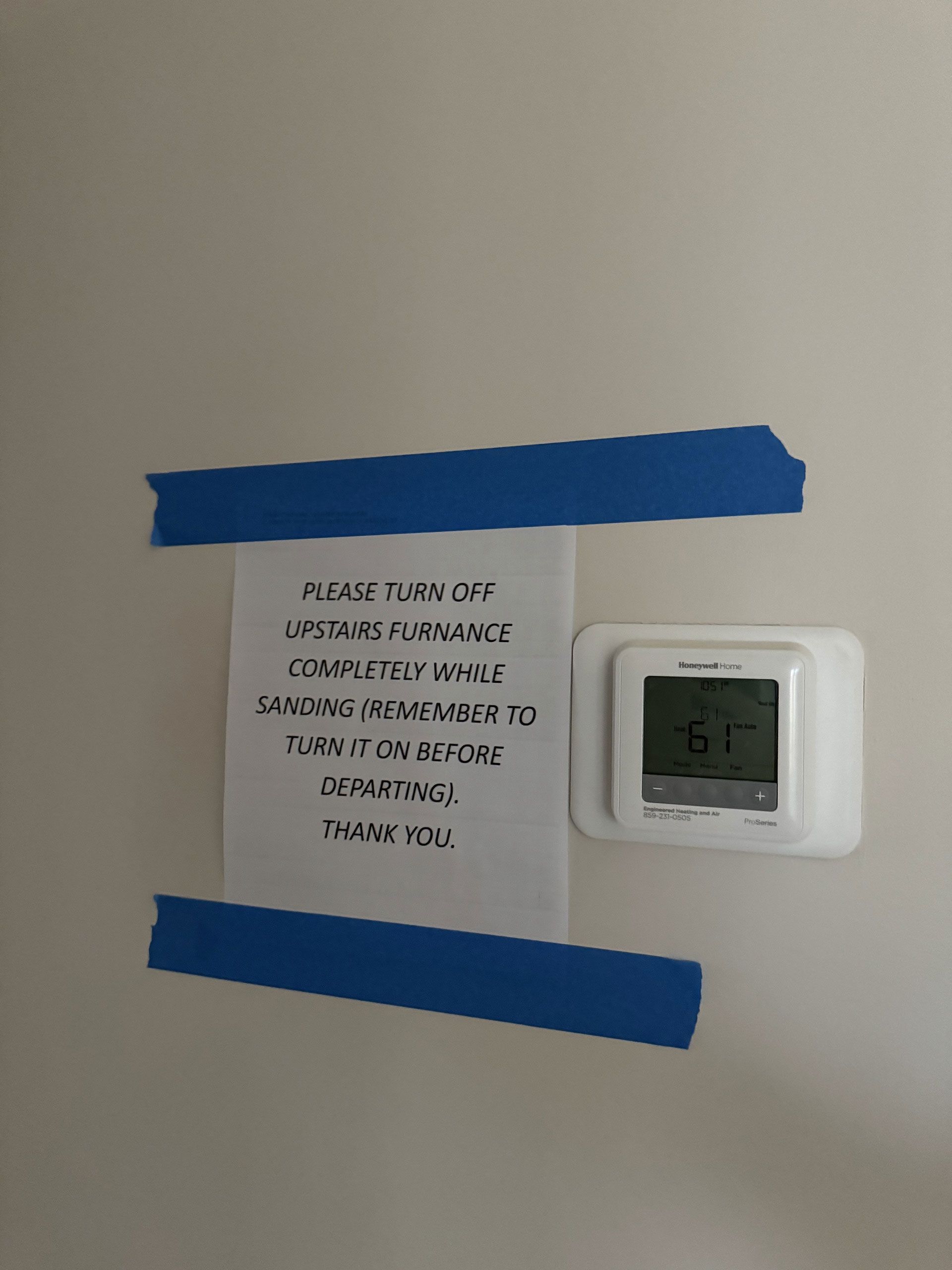 A piece of paper taped to a wall next to a thermostat