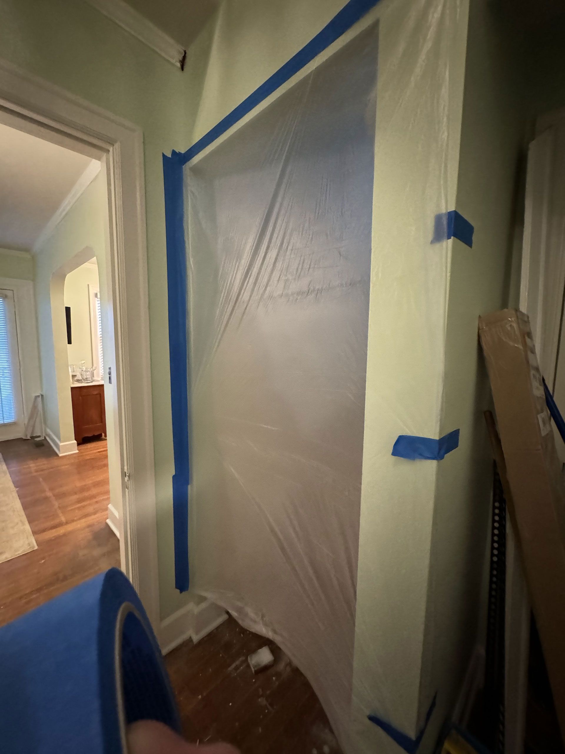 A person is holding a roll of blue tape in a room