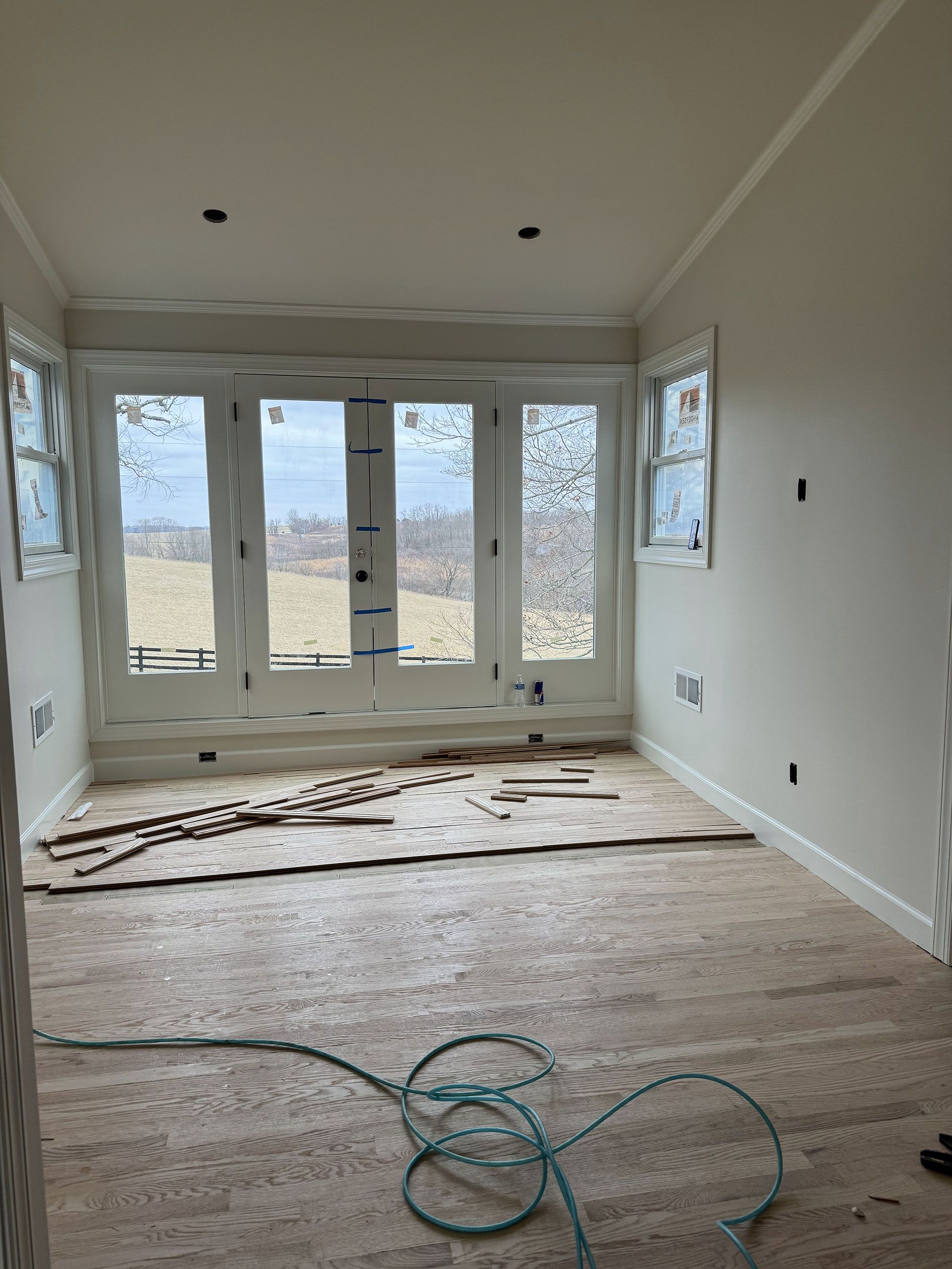 An empty room with a lot of windows and a hose on the floor.