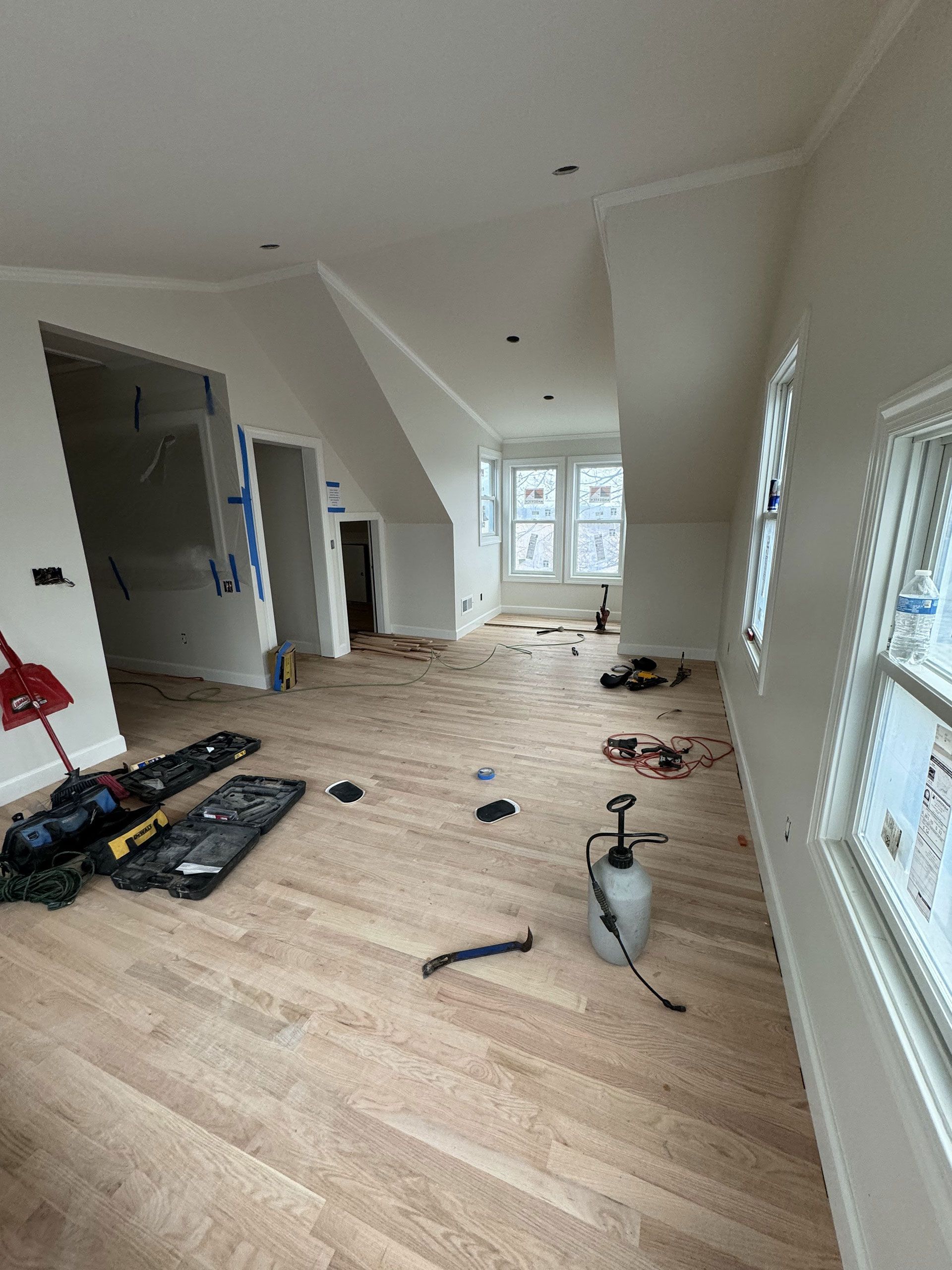 A large room with hardwood floors and white walls is being remodeled