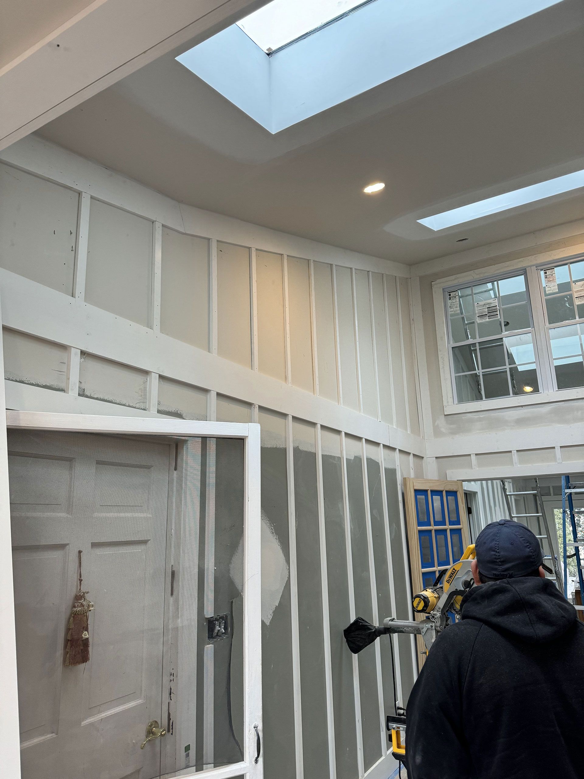 A man is standing in a room with a skylight in the ceiling