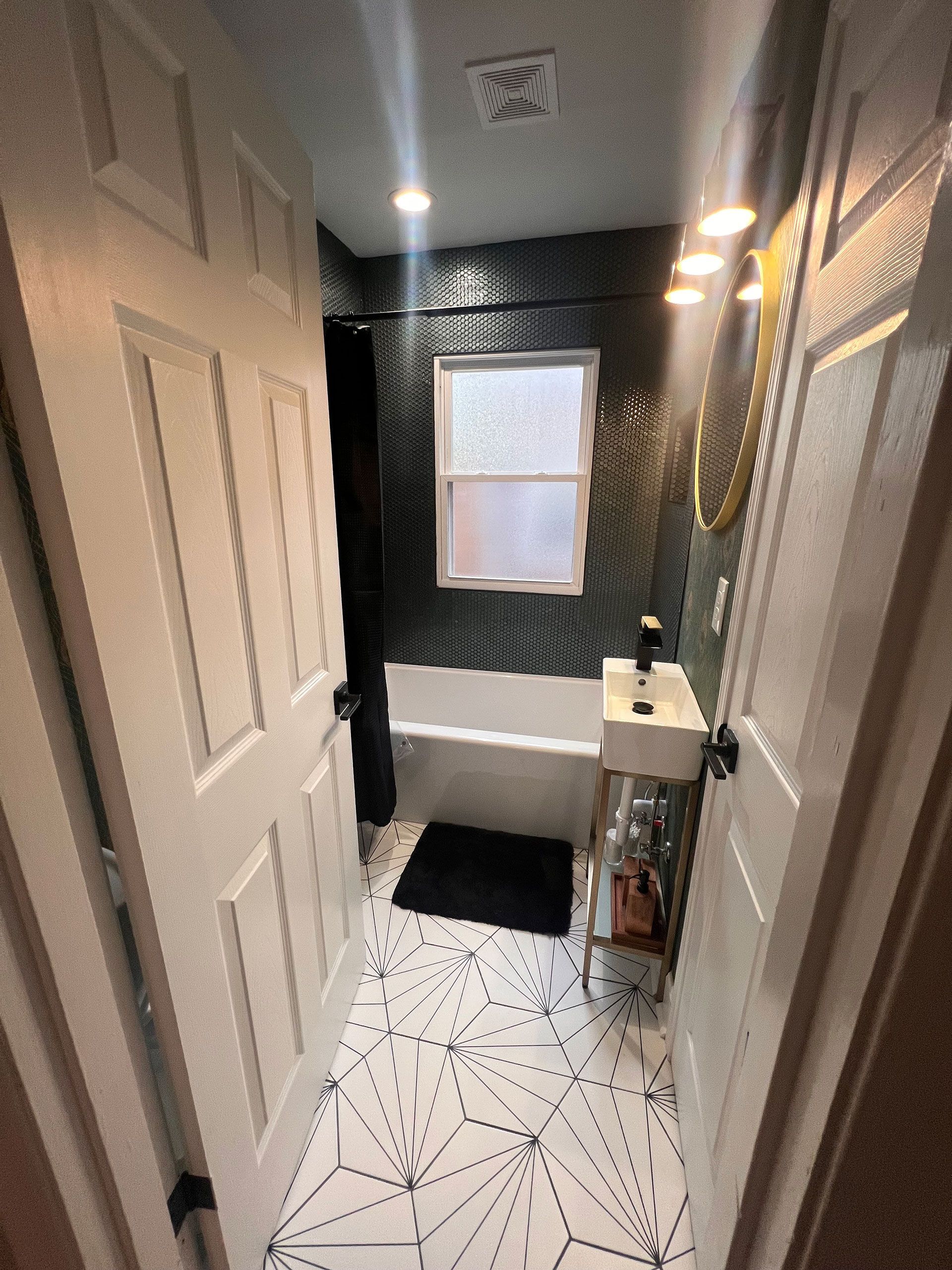 A bathroom with a tub, sink, mirror and window