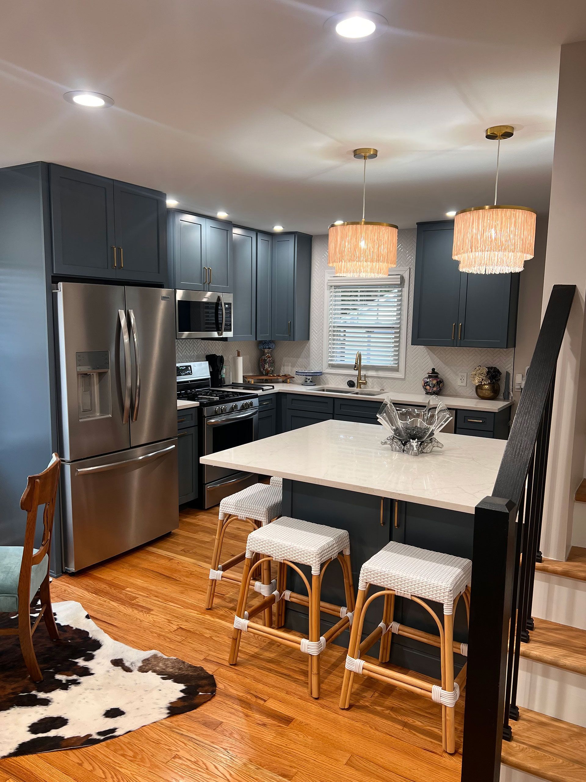 A kitchen with stainless steel appliances, a large island, and a cowhide rug