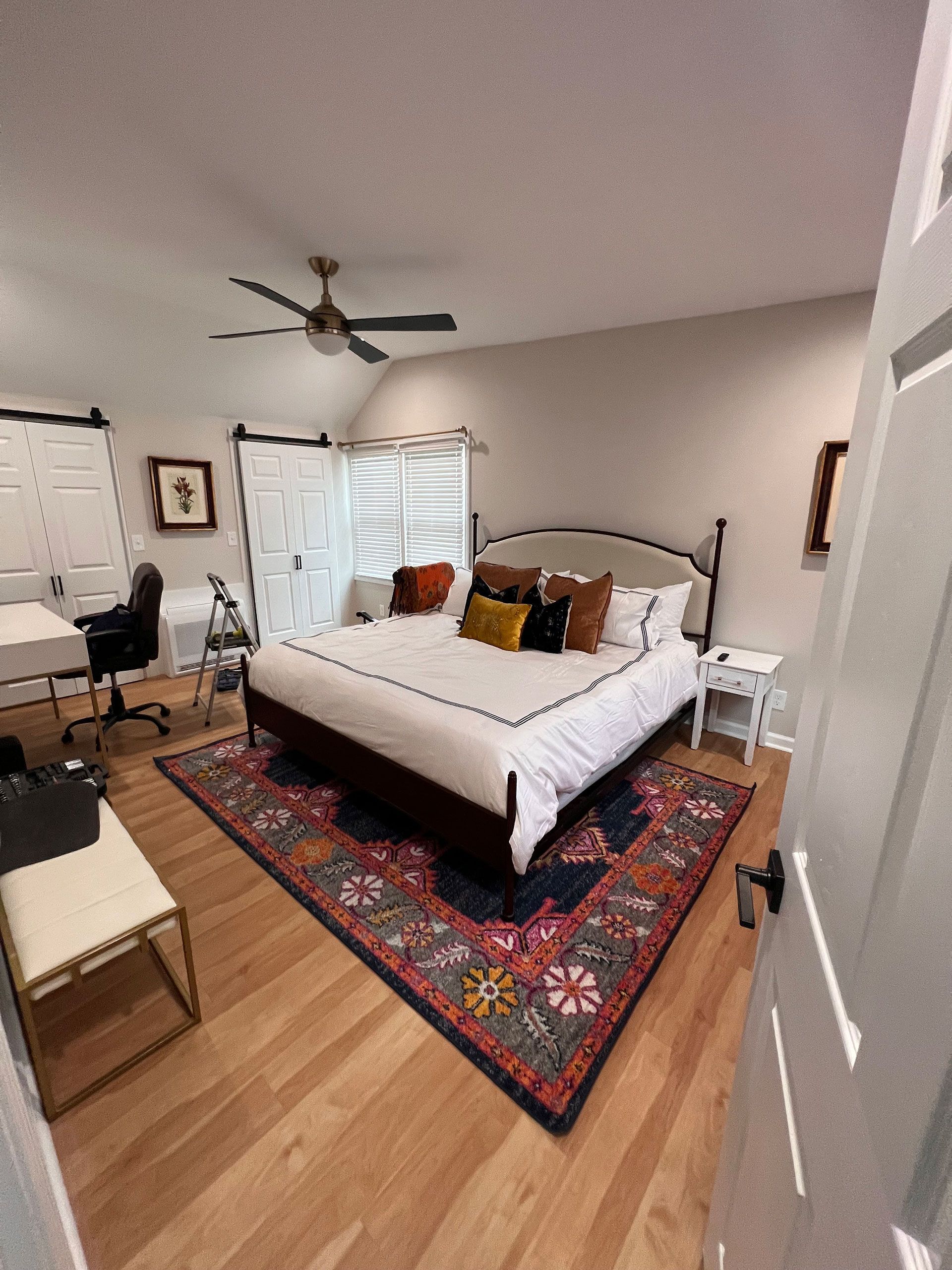 A bedroom with a king size bed and a rug on the floor