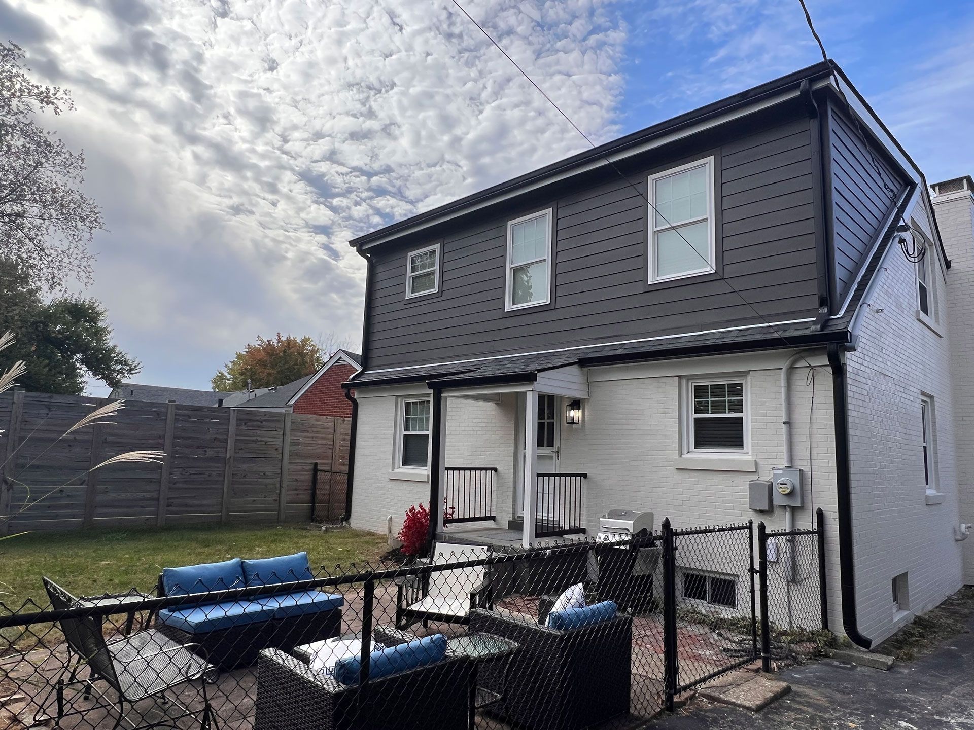 A white house with a black roof and a patio area in front of it