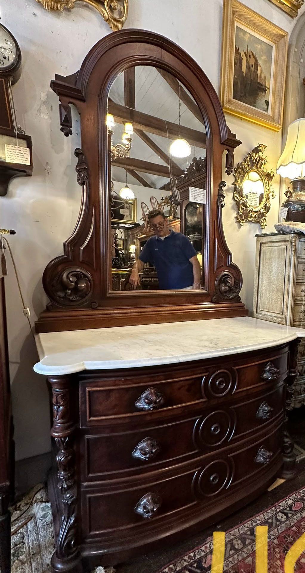 A man is standing in front of a large mirror on a dresser