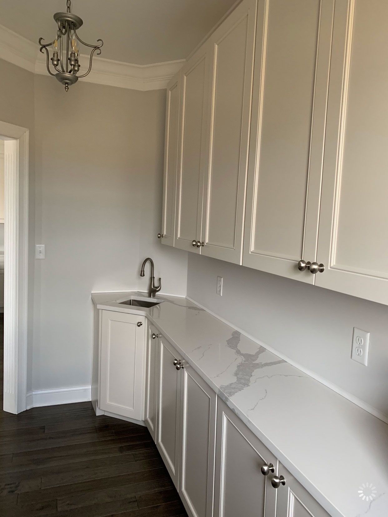 A kitchen with white cabinets, marble counter tops, and a sink