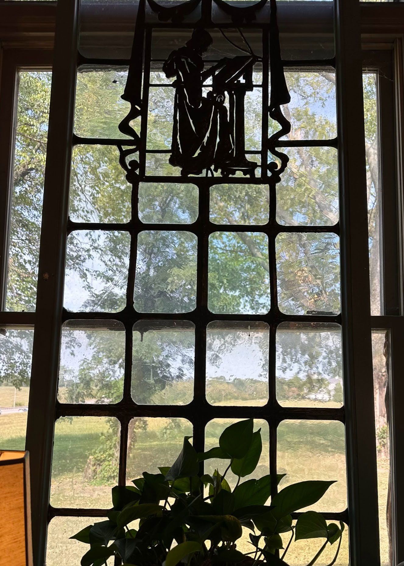 A stained glass window with a plant in front of it