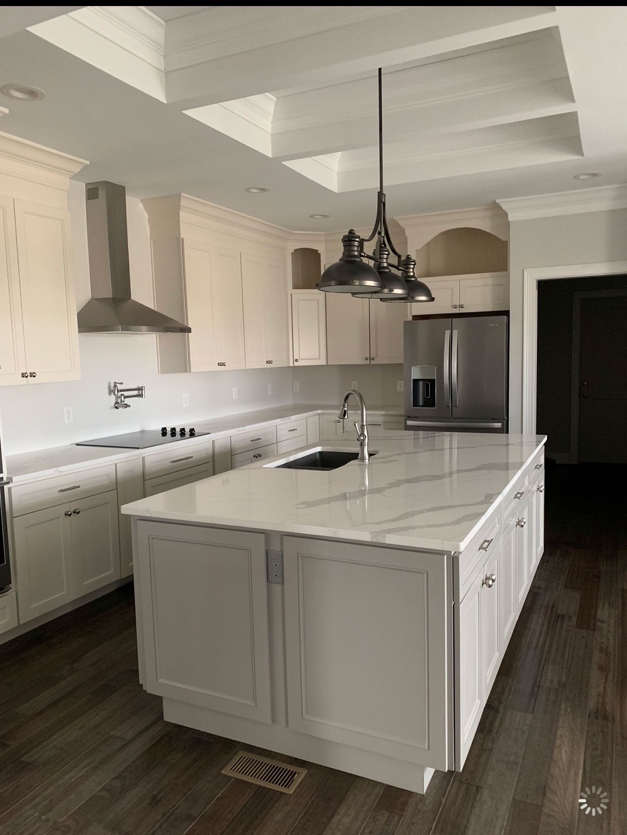 A kitchen with white cabinets and a large island in the middle