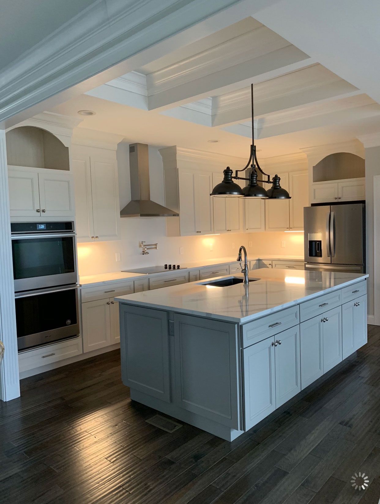 A kitchen with white cabinets and a large island in the middle