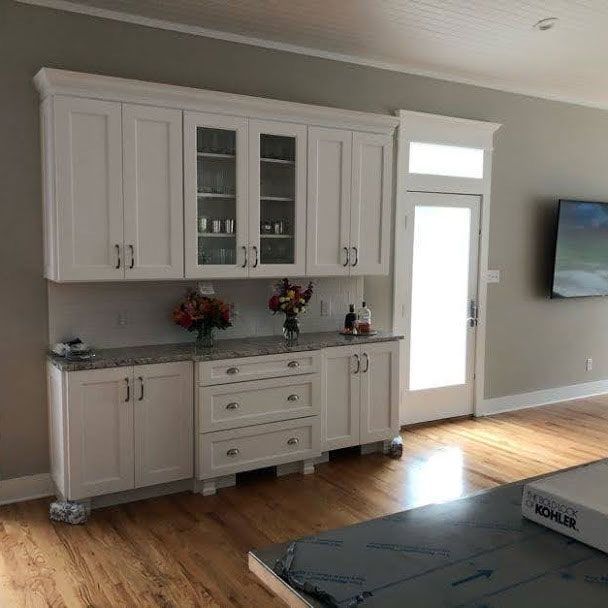 A kitchen with white cabinets and a tv on the wall