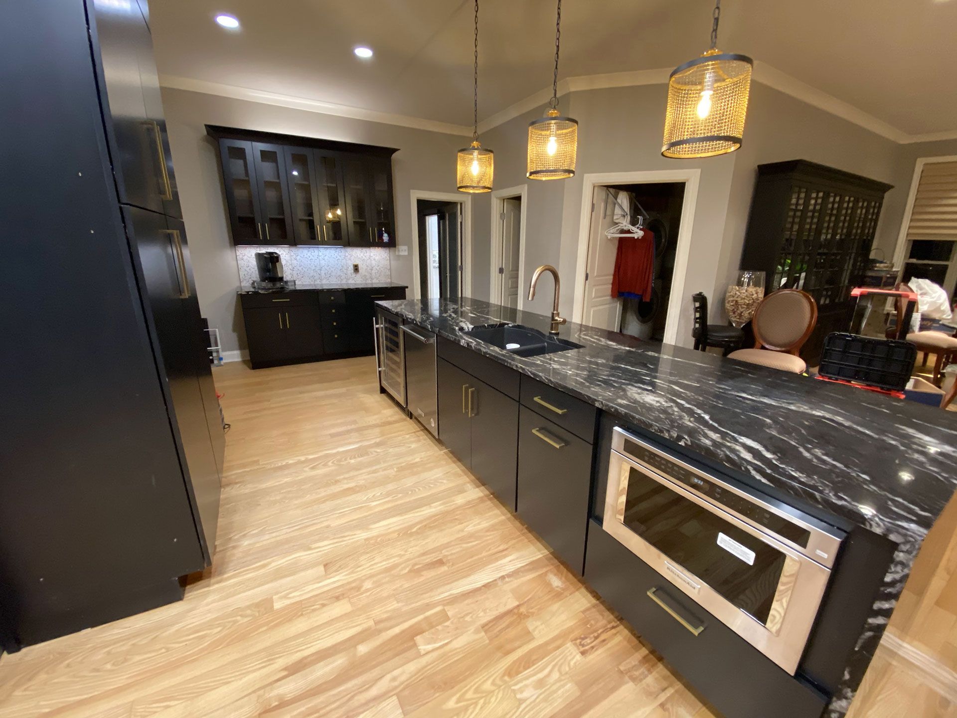 A kitchen with black cabinets, granite counter tops, and stainless steel appliances