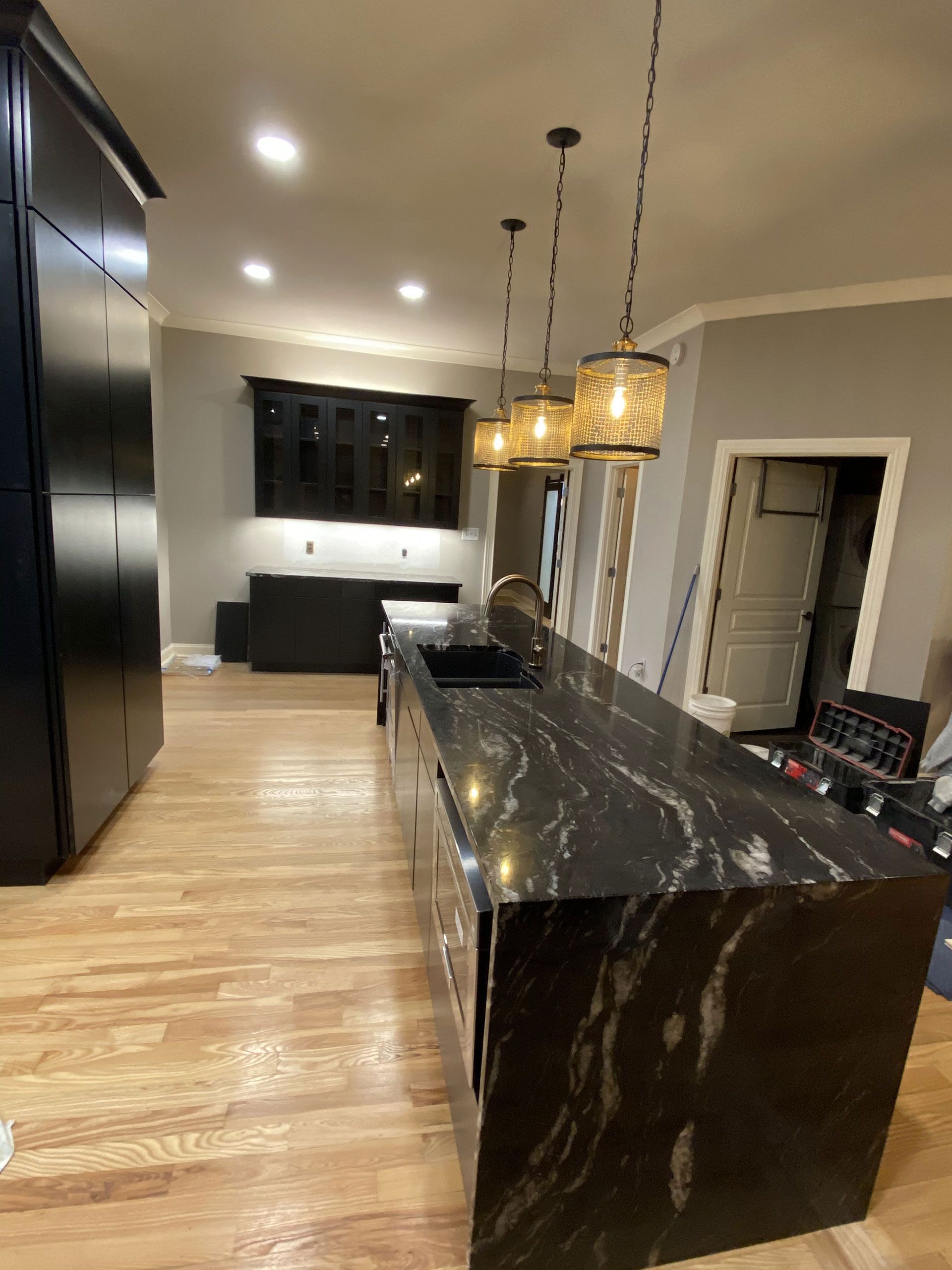 A kitchen with a black granite counter top and wooden floors