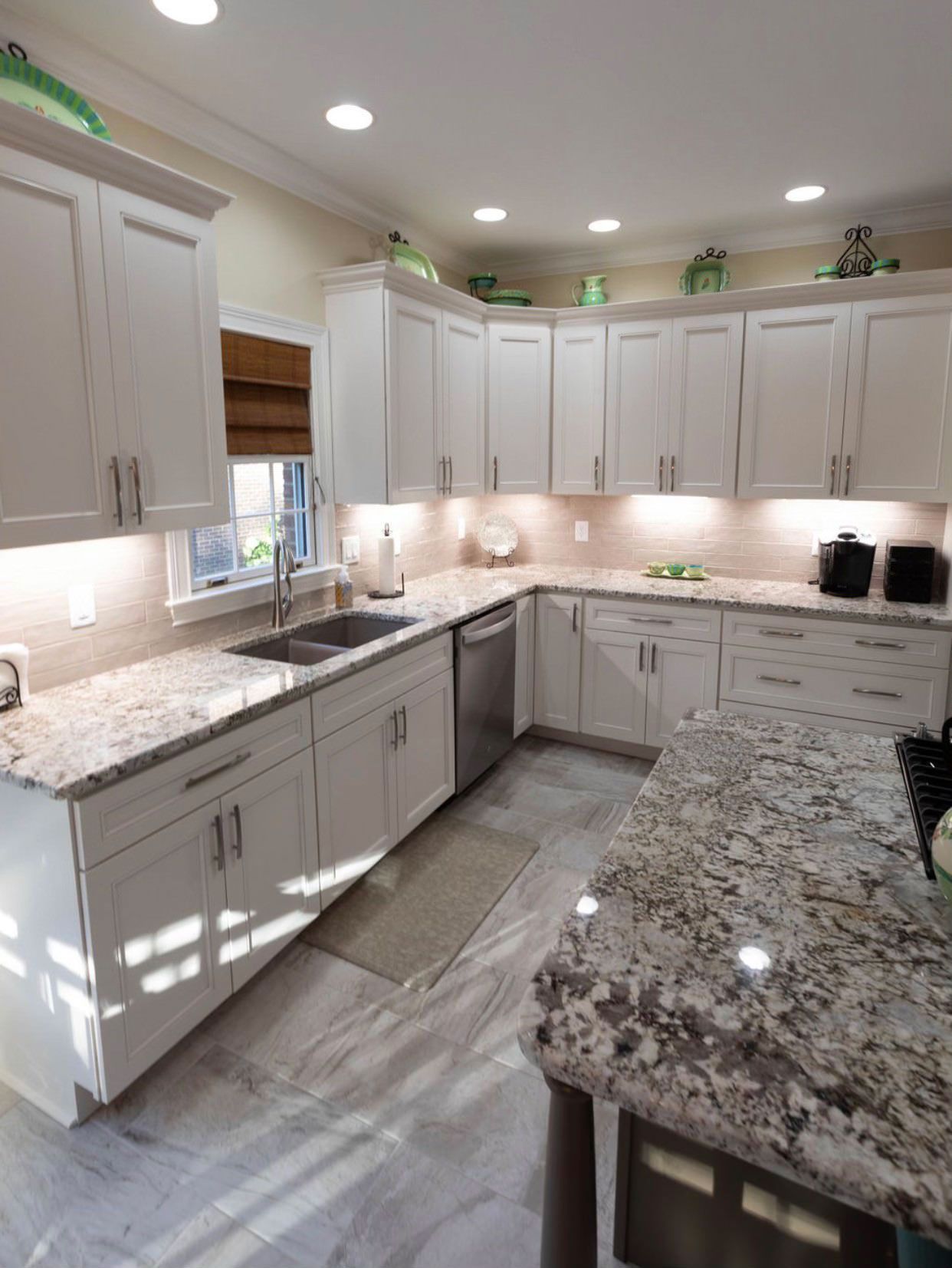 A kitchen with granite counter tops and white cabinets