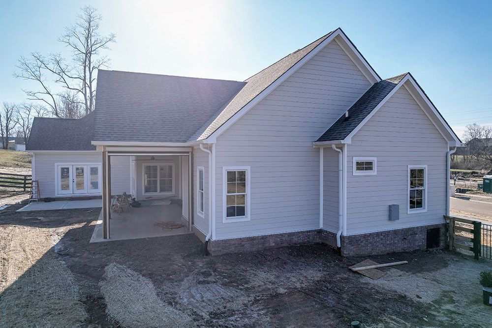 The back of a white house with a covered porch and a lot of windows.