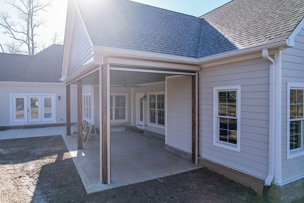 A white house with a covered patio in front of it.