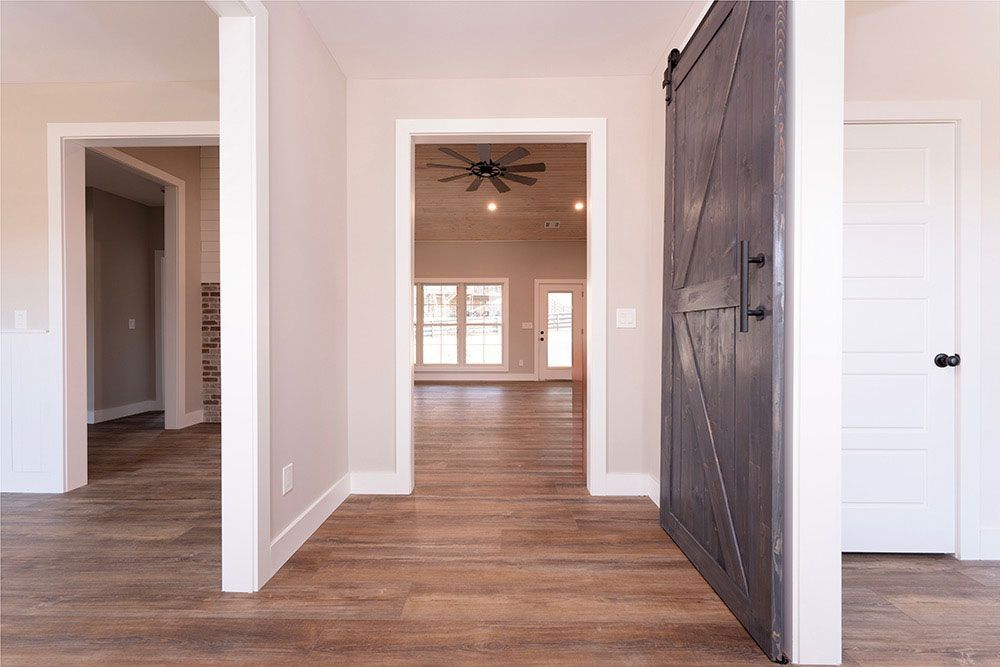 A hallway in a house with a sliding barn door and a ceiling fan