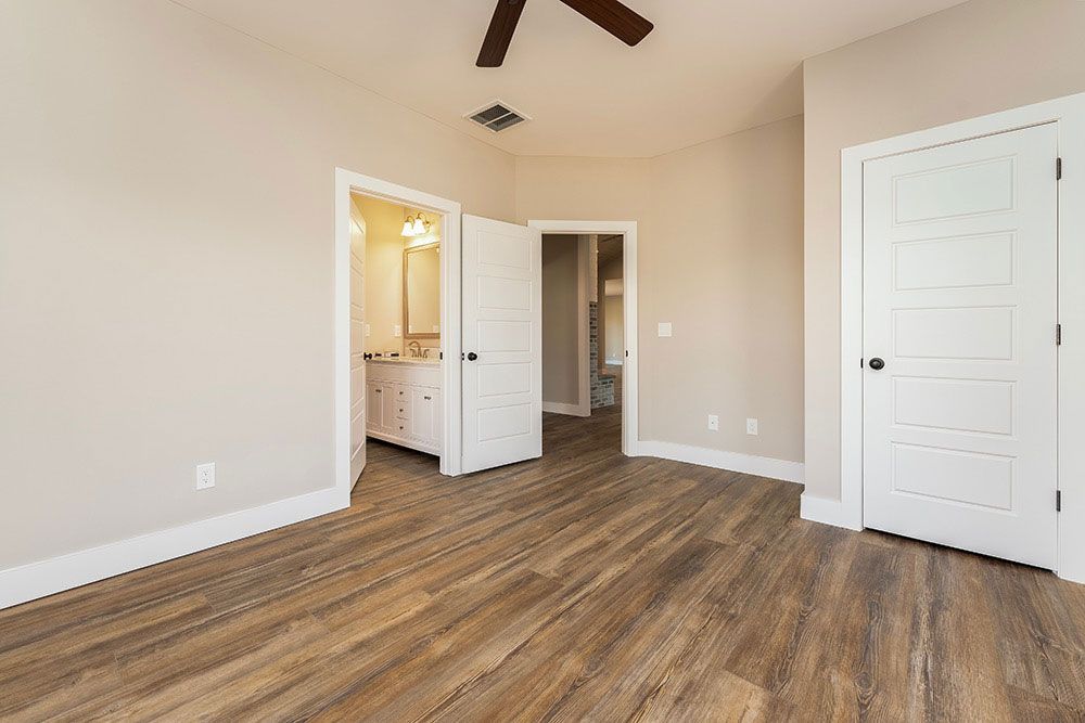 An empty bedroom with hardwood floors and a ceiling fan.