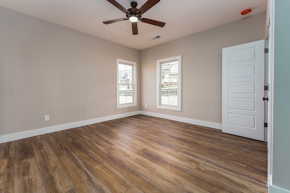 An empty room with hardwood floors and a ceiling fan