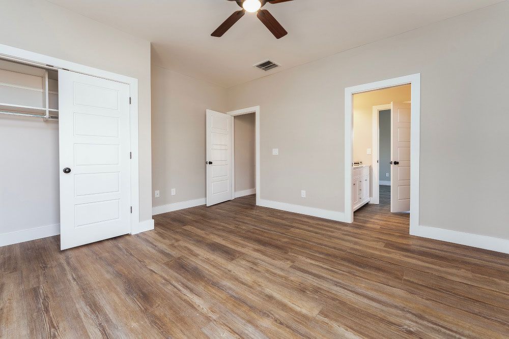 An empty bedroom with hardwood floors and a ceiling fan