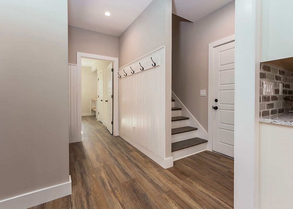 A hallway with hardwood floors and stairs in a house.