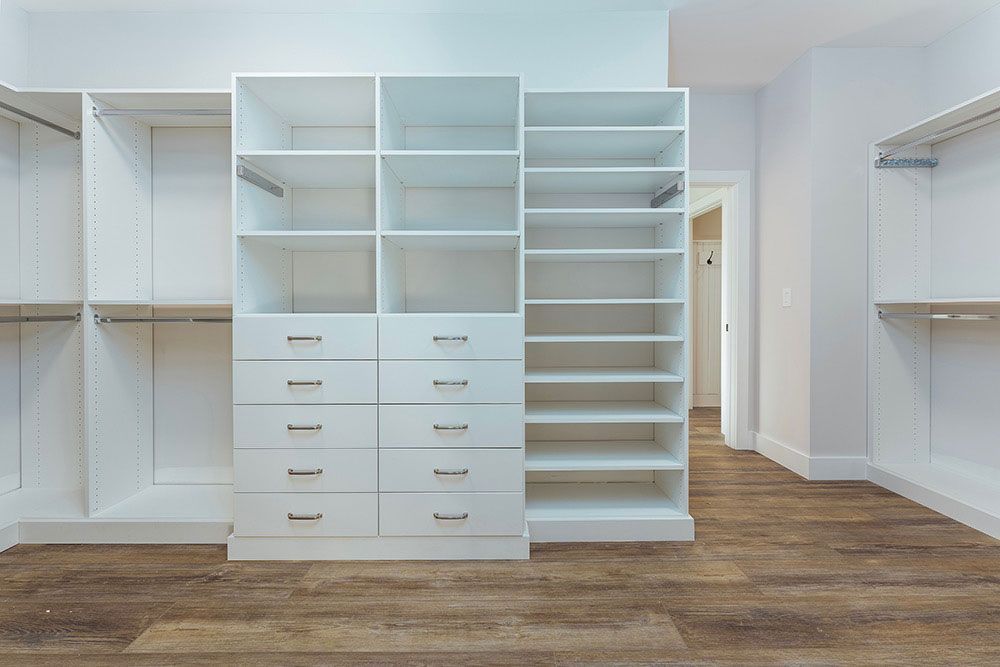 A walk in closet with lots of shelves and drawers