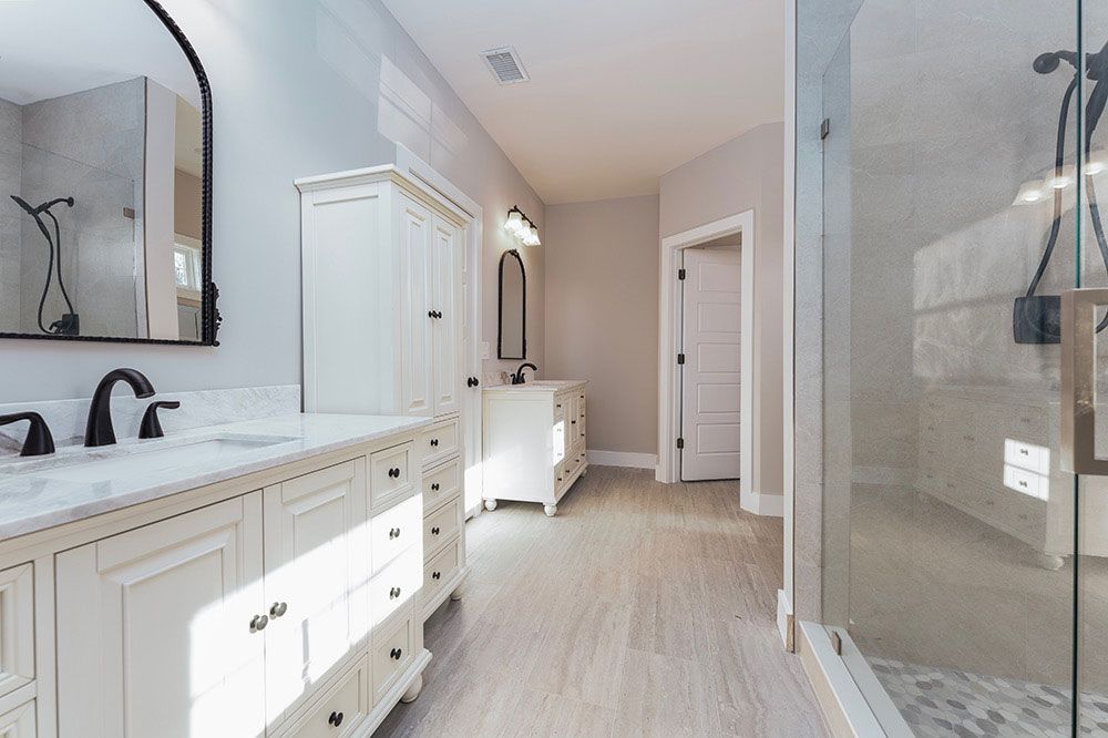 A bathroom with two sinks and a walk in shower.
