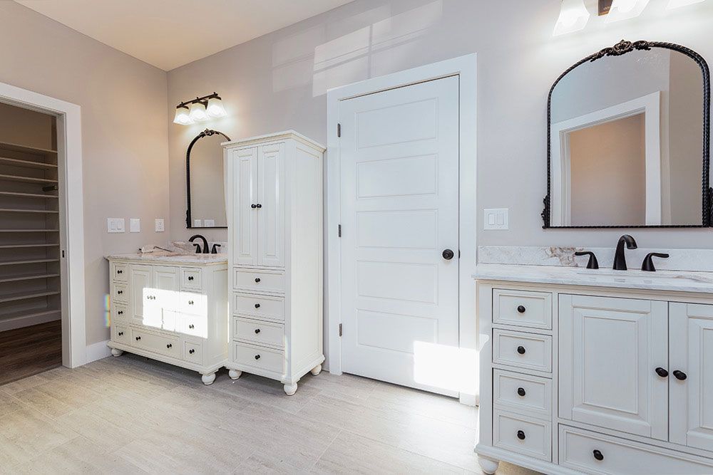 A bathroom with two sinks, two mirrors and a walk in closet