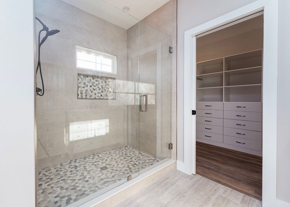 A bathroom with a walk in closet and a shower with a glass door