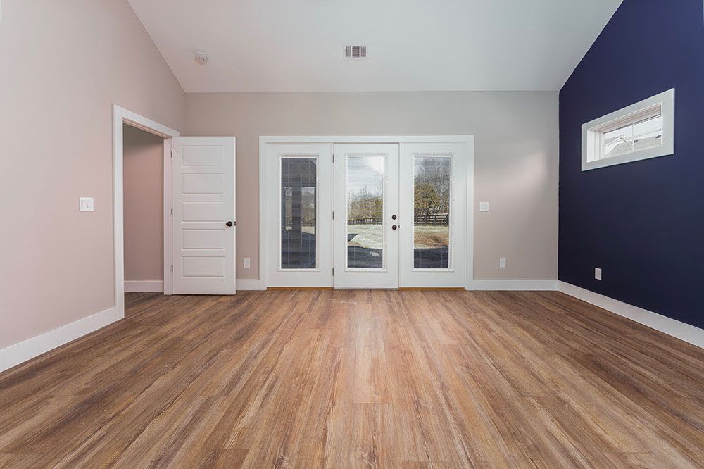 An empty room with hardwood floors and a blue wall.