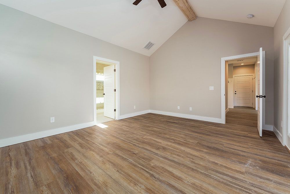 A large empty room with hardwood floors and a vaulted ceiling