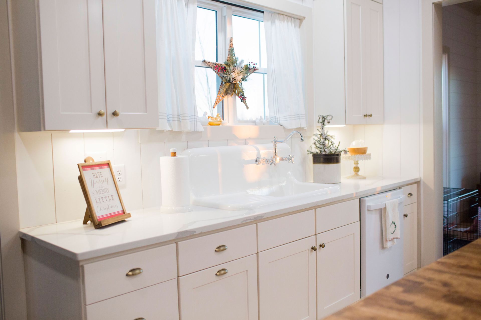 A kitchen with white cabinets, a sink, a dishwasher, and a window
