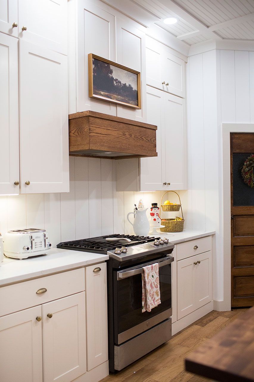 A kitchen with white cabinets, a stove, a toaster and a picture on the wall above the stove