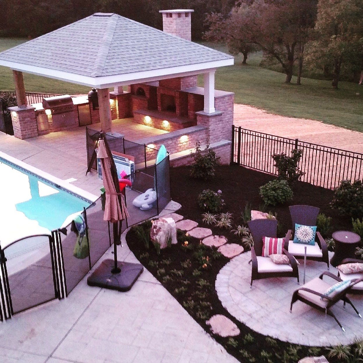 A large swimming pool with a gazebo in the background surrounded by trees