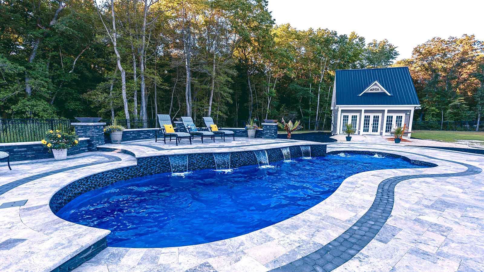 A large swimming pool with a gazebo in the background surrounded by trees.