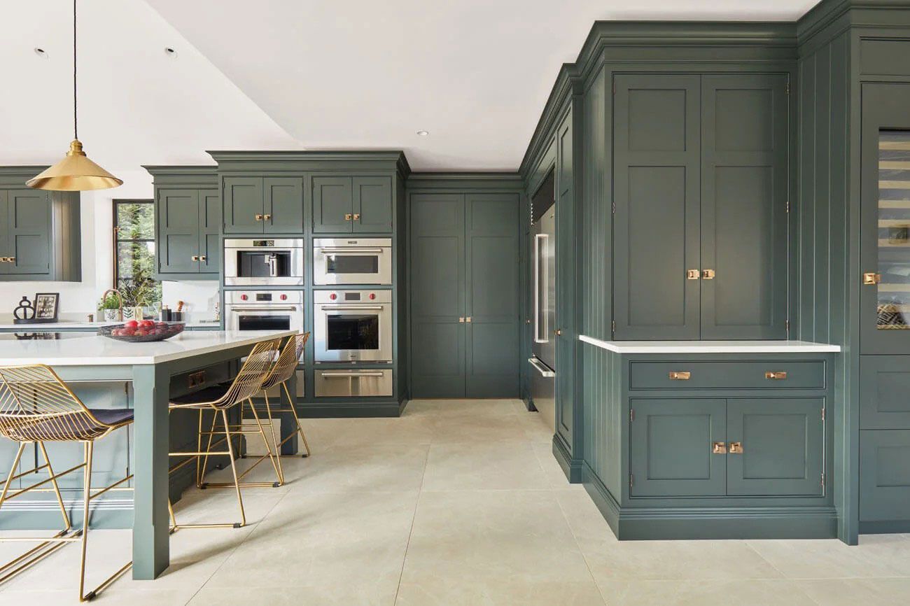 A kitchen with green cabinets and stainless steel appliances