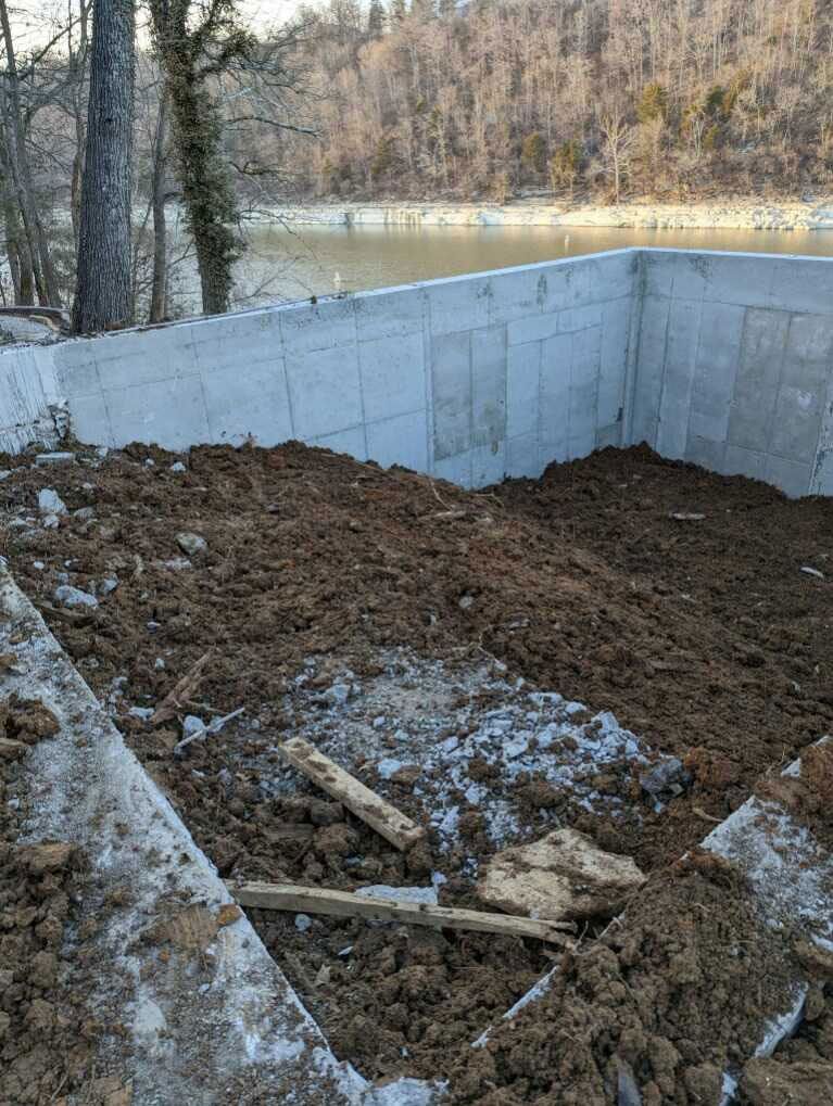 A pile of dirt is sitting in front of a concrete wall