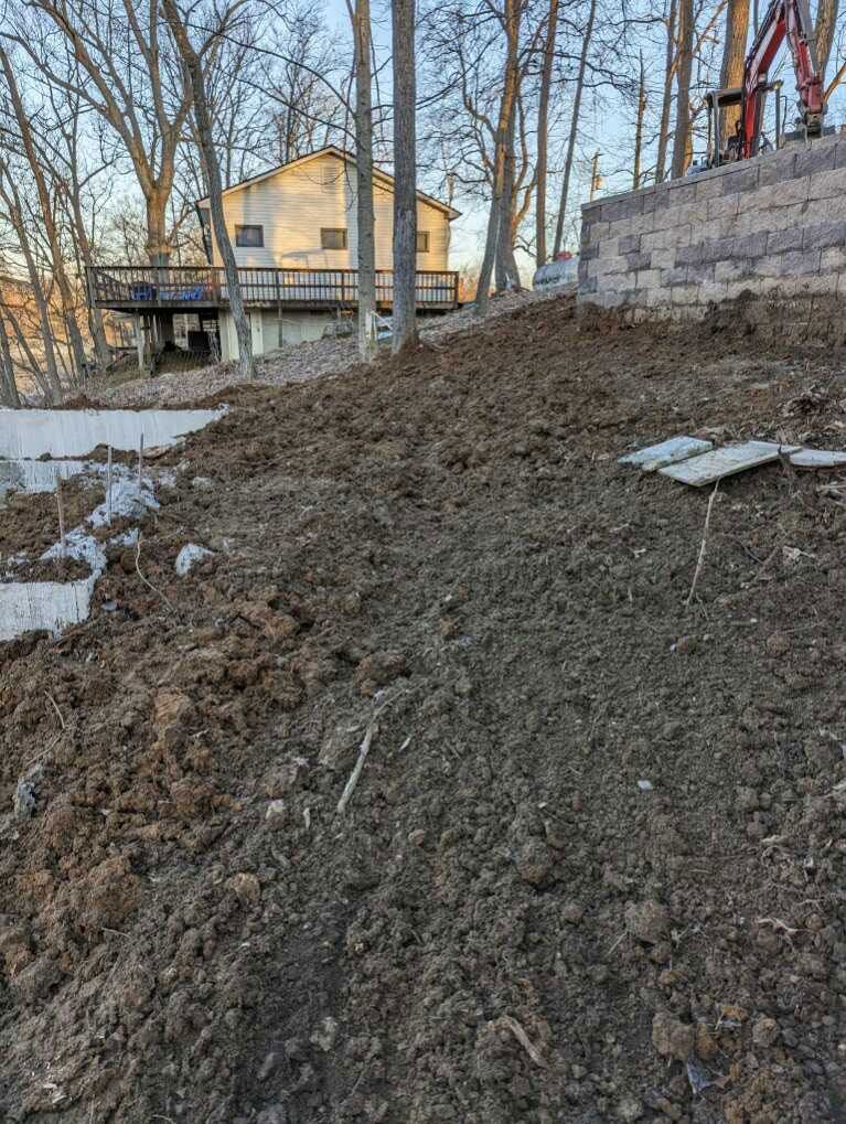 A pile of dirt is sitting on top of a hill next to a house