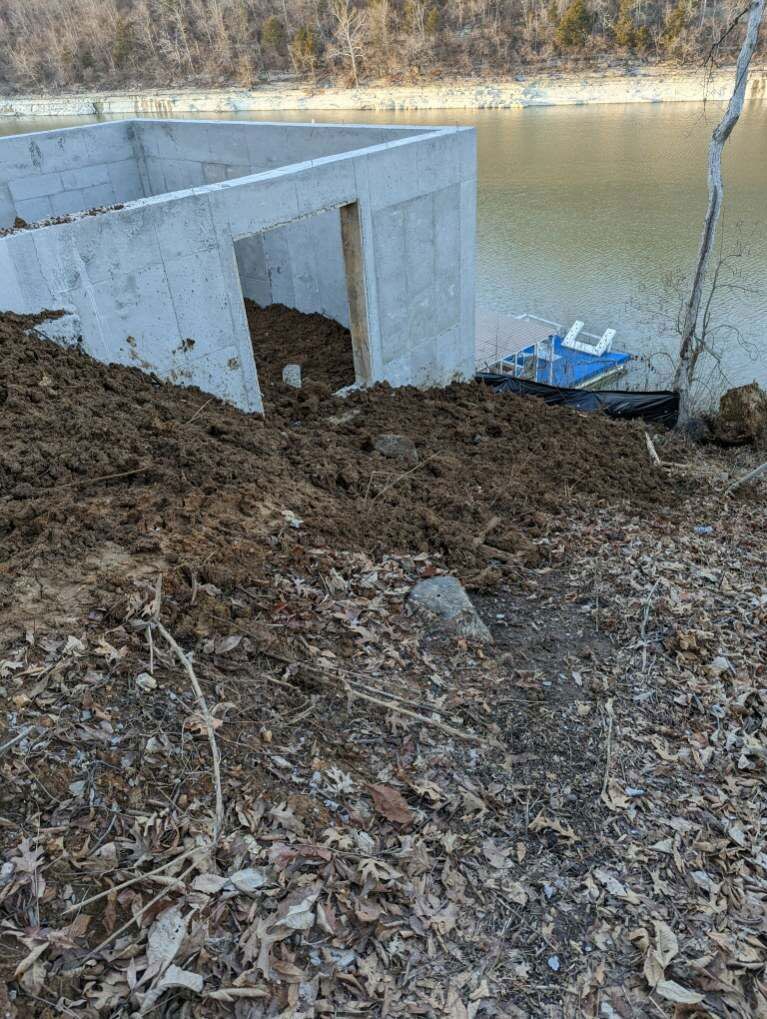 A pile of dirt is sitting next to a body of water