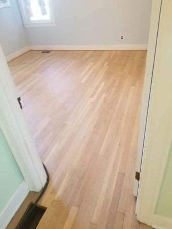 A bedroom with hardwood floors and a window