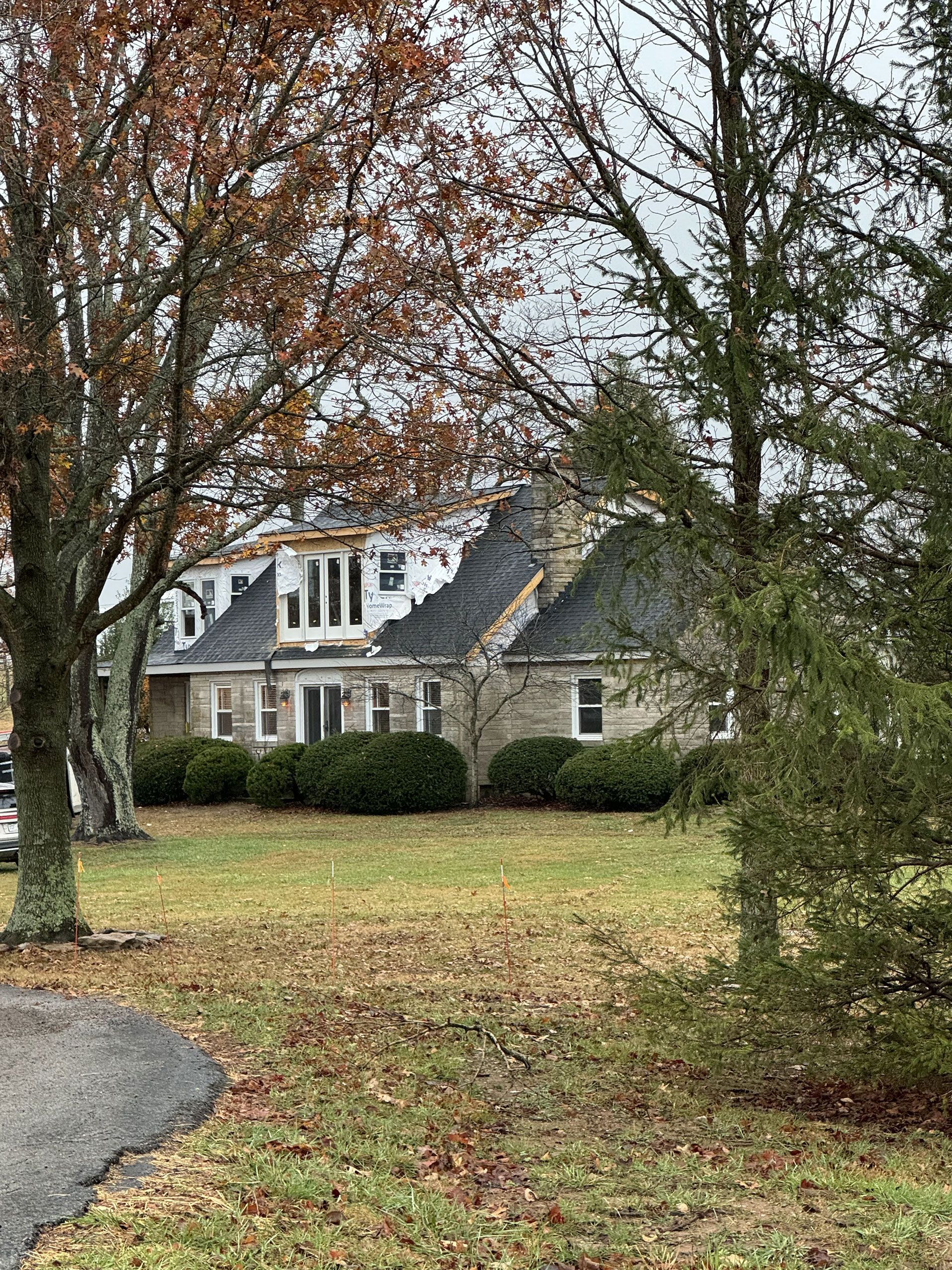 A large house is sitting on top of a lush green field surrounded by trees