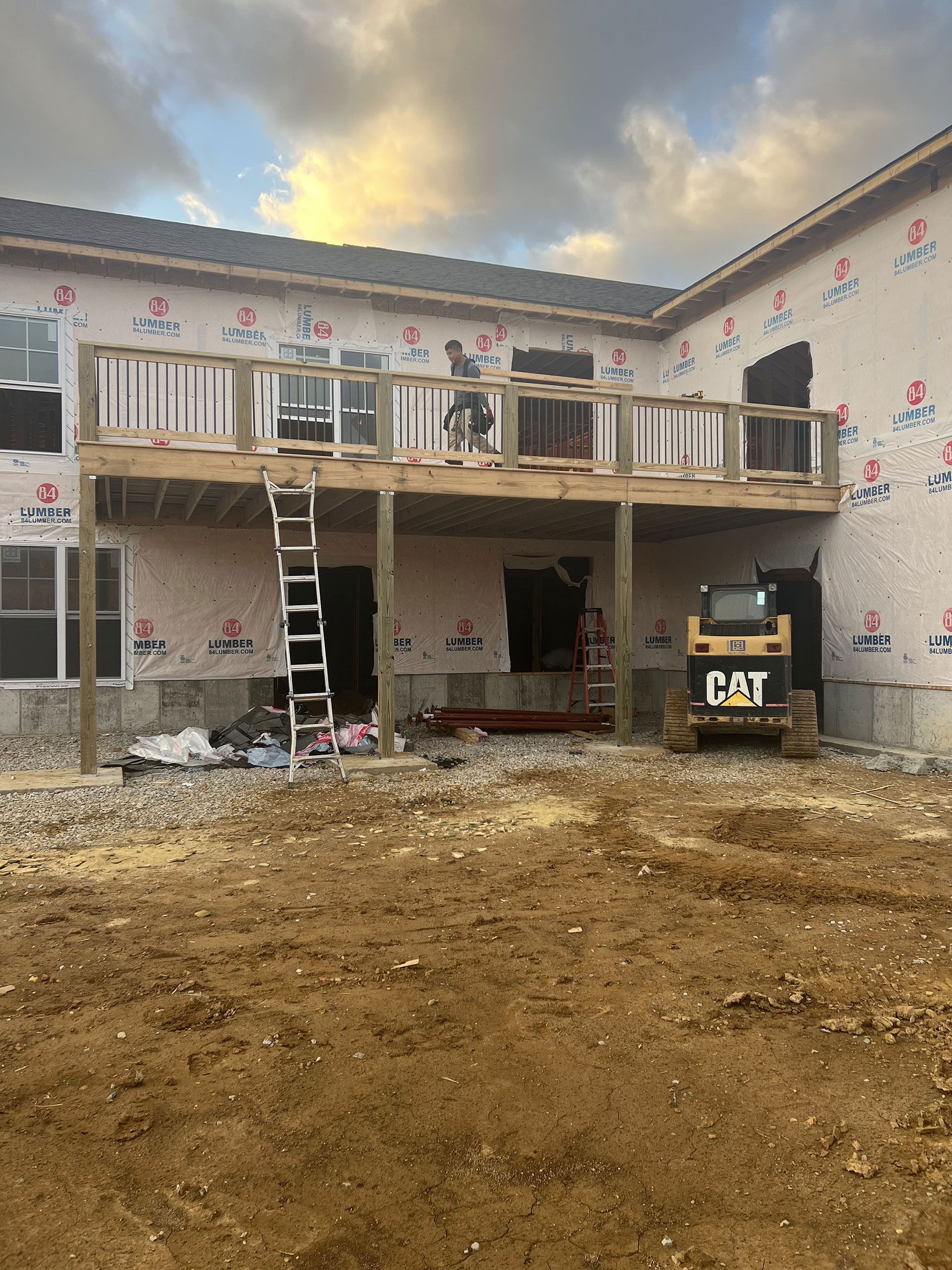 A cat bulldozer is parked in front of a house under construction