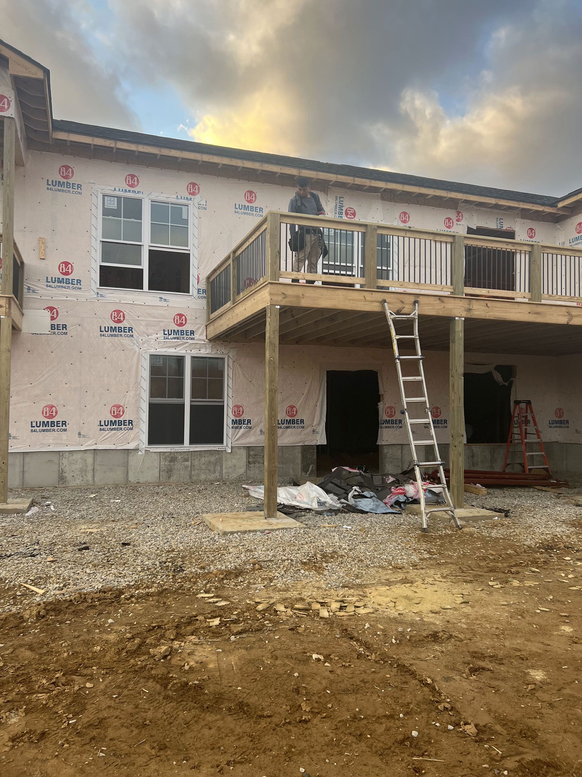 A house under construction with a deck and a ladder in the dirt