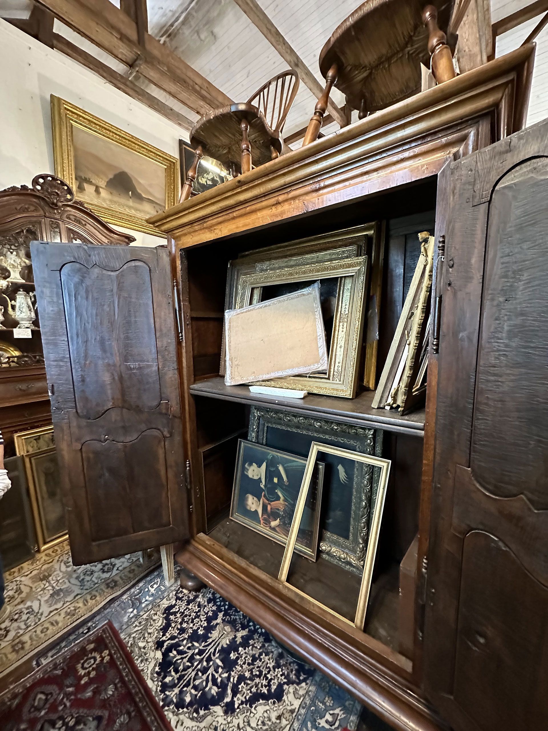 A wooden cabinet filled with pictures and frames in a room.