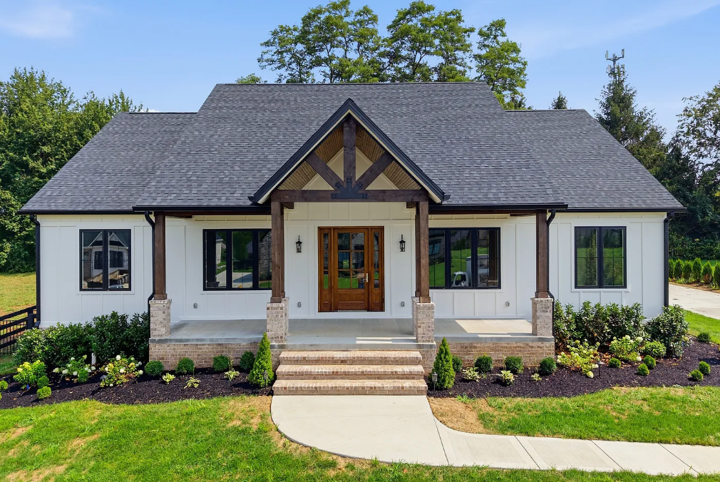 Single-story house with gray roof, white siding, and a landscaped front yard.