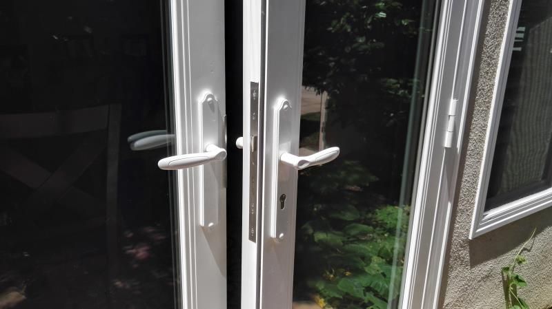 Open glass double doors with silver handles, leading to a dark outdoor patio area.