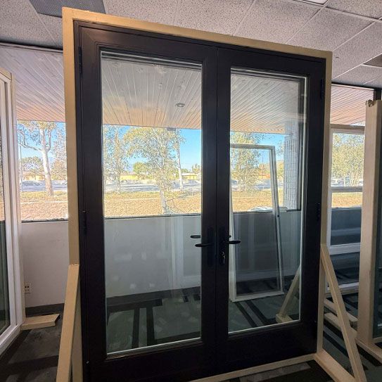 Black-framed glass double door standing in an office showroom with windows behind it