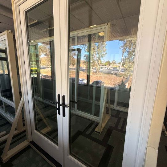 Glass double doors with black handles, reflecting an outdoor construction site.