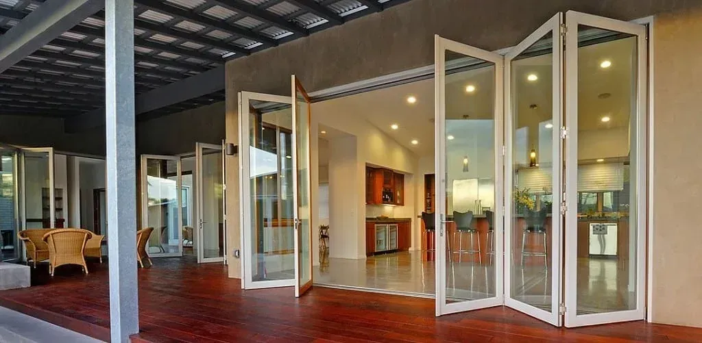 Glass storefront with open white doors and warm interior lighting under a covered walkway