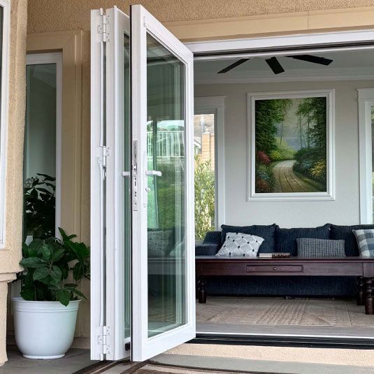 Open patio door to a bright porch with a bench, plant, and framed landscape art inside.